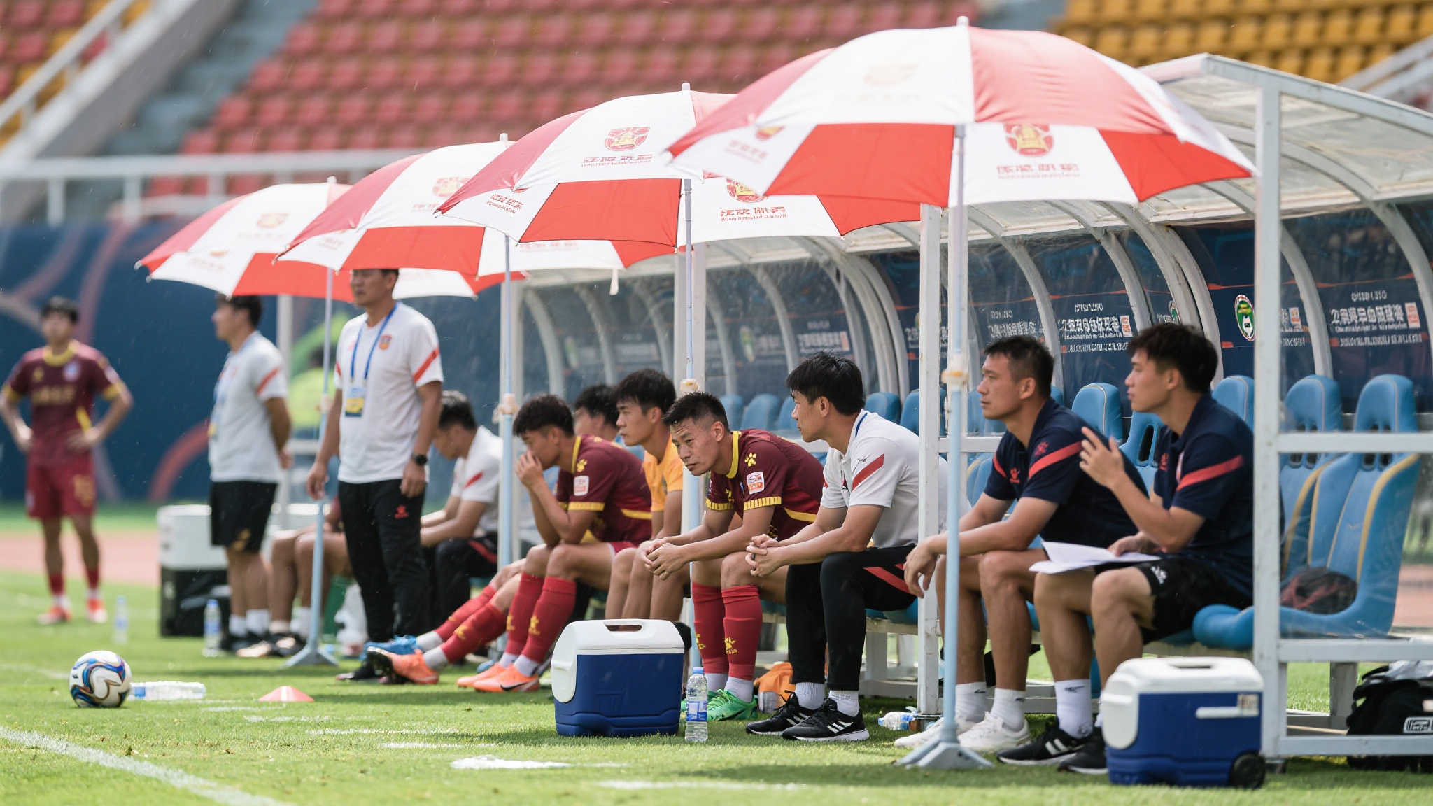 为了应对高温，球队工作人员为替补席准备了遮阳伞，确